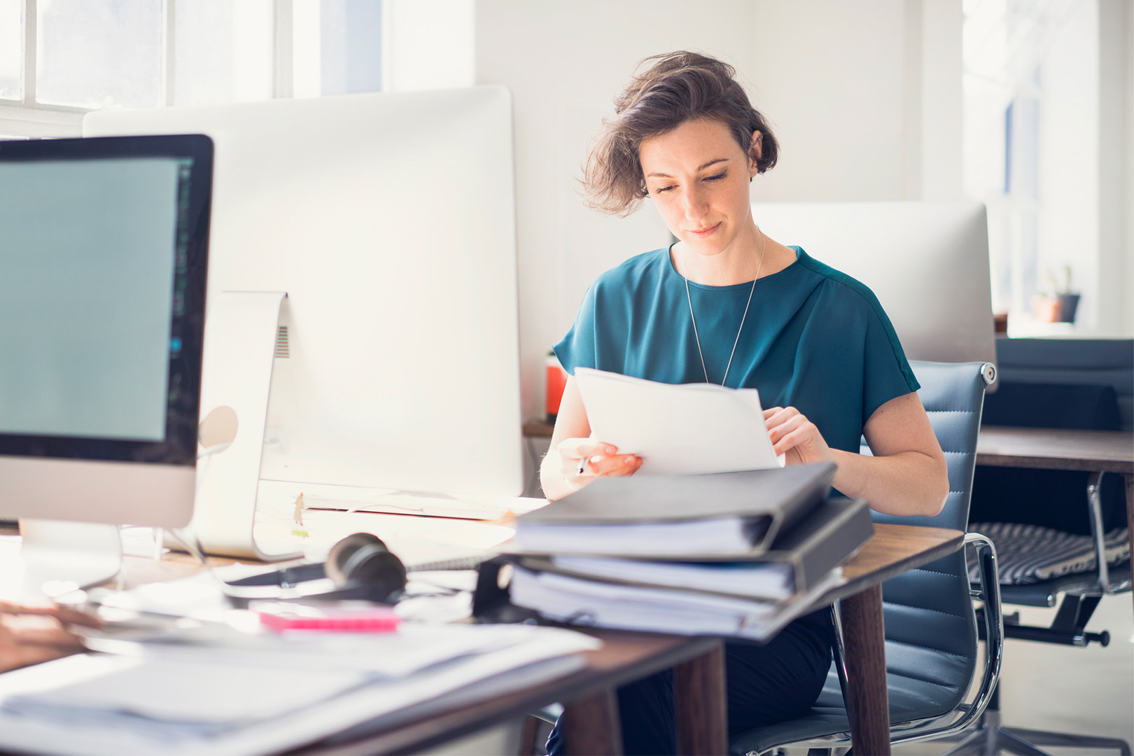 A woman seated at a desk looking through paperwork