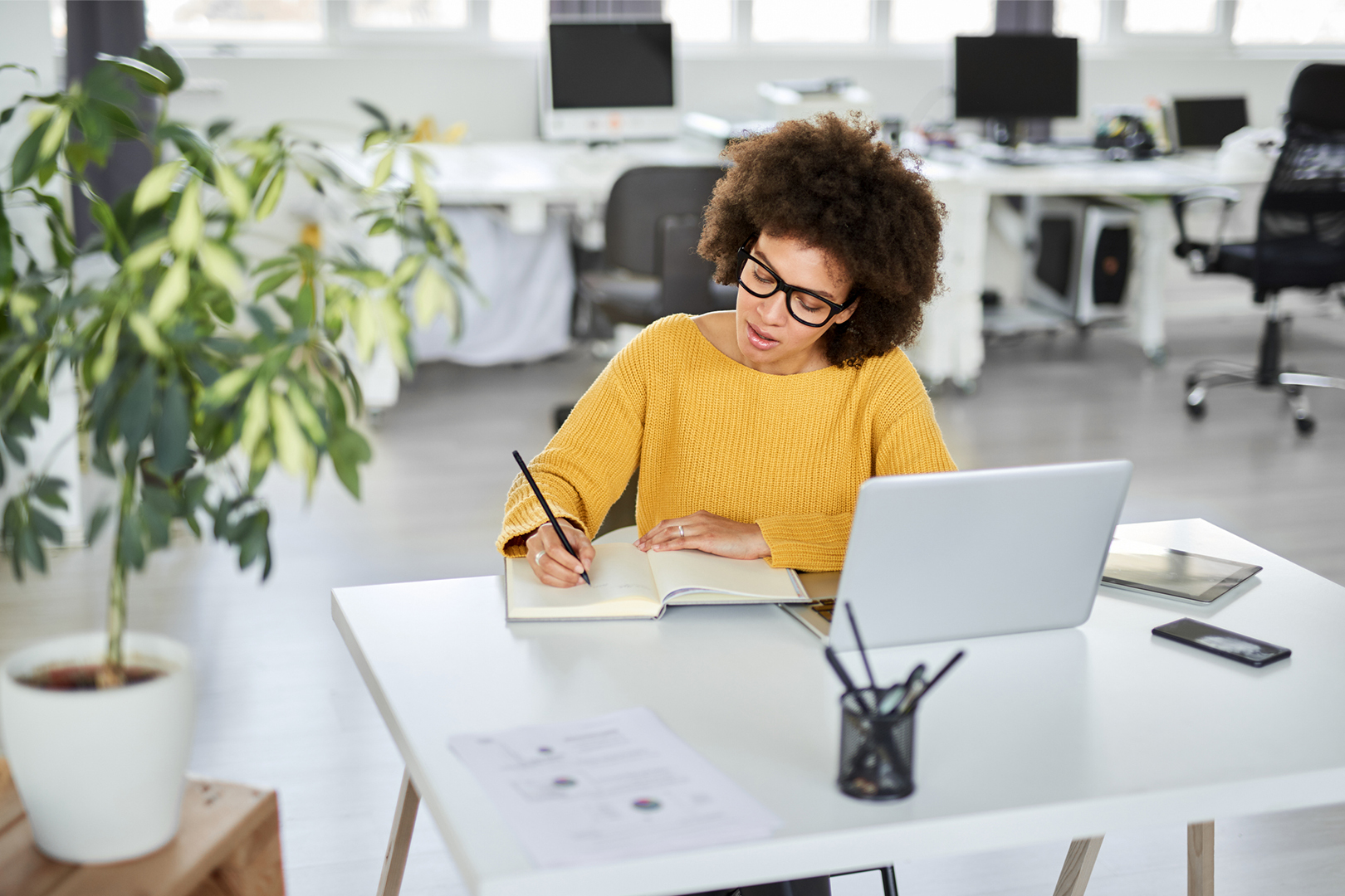 A woman seated at a table writing notes.