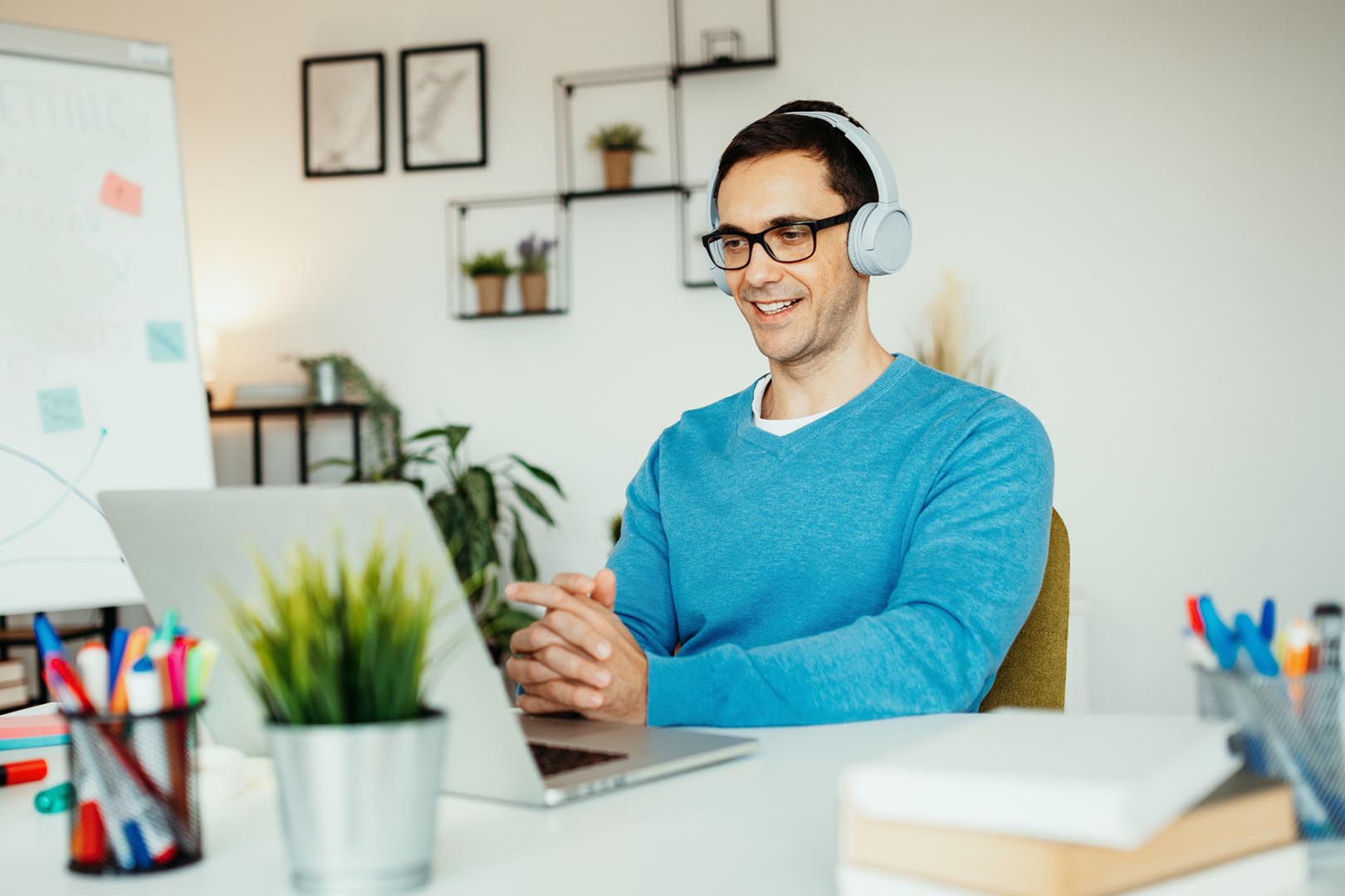 Person with headphones on behind a computer screen