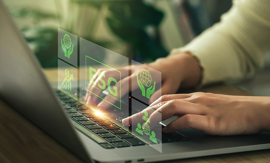 Close up shot of a person typing on computer with green ESG graphic floating above the keyboard. 