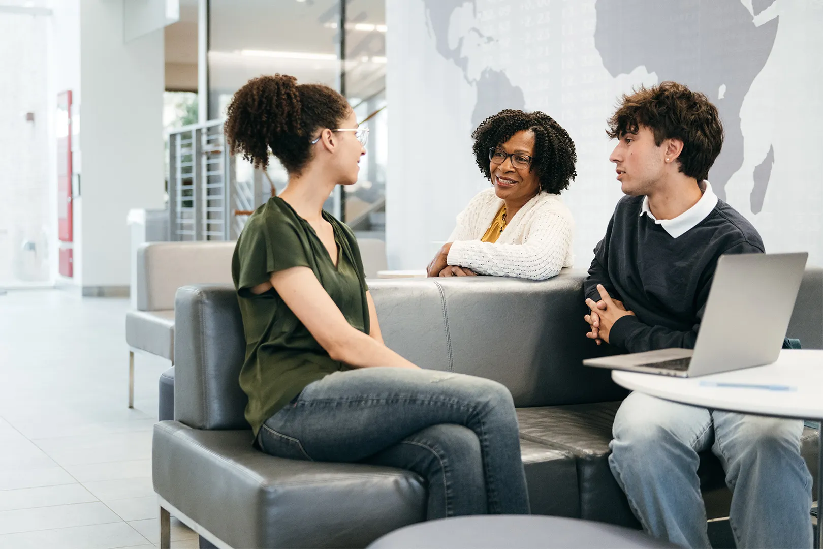 Three people seated on a couch having a conversation
