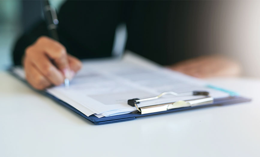 A person filling in a form on a clipboard