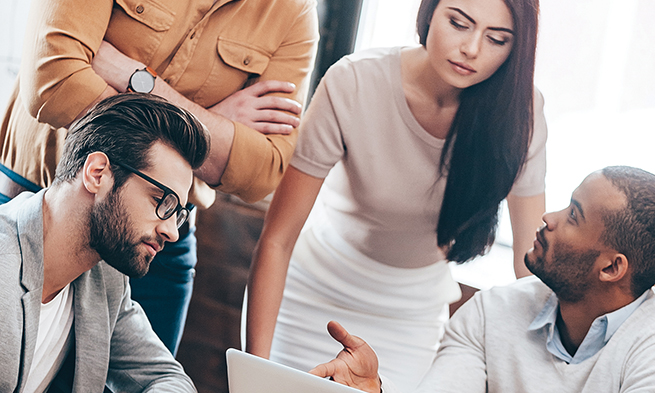 A group of people meeting around a computer